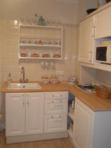 La cuisine est équipée de placards blancs, d'un évier et d'un four micro-ondes. dans l'établissement Apartmán Nostalgie, à Telč