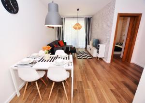 隱海市的住宿－Apartament 27 Dwie Sosny，用餐室以及带白色桌椅的起居室。