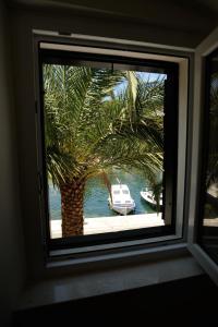 a window with a palm tree and a boat in the water at Vila Marija in Supetar