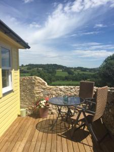 a patio with a table and chairs on a deck at The Retreat in Charmouth