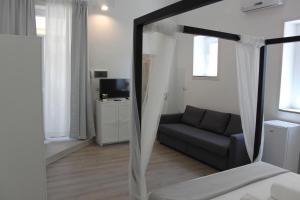 a bedroom with a bed and a couch and a television at Dimora di Artemide in Siracusa