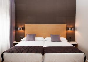 1 dormitorio con 1 cama grande y cabecero de madera en Hotel Universal en Santiago de Compostela