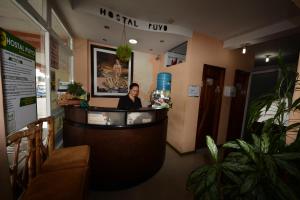 普约Hostal Puyo的坐在餐厅接待台的男人
