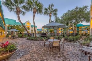 a patio with tables and chairs and palm trees at Best Western Seaway Inn in Gulfport