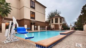a swimming pool with a blue chair at Best Western Plus North Houston Inn & Suites in Houston