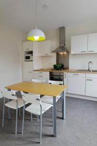 een keuken met een houten tafel en witte kasten bij Aux Herbes Folles in Herve