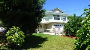 une maison blanche avec une pelouse devant elle dans l'établissement Crown House B&B, à Lake Cowichan