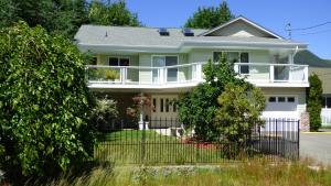 une maison blanche avec une clôture devant elle dans l'établissement Crown House B&B, à Lake Cowichan