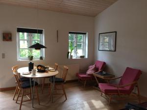 a room with a table and chairs and windows at LindegaardApartment - woods and sea in Hejls