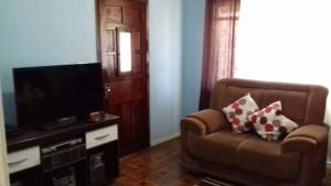 a living room with a chair and a flat screen tv at Orquidea Hospedagem in Cachoeira Paulista