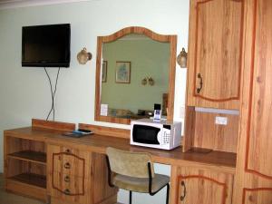 a microwave sitting on a wooden desk with a mirror at The Nambucca Motel in Nambucca Heads