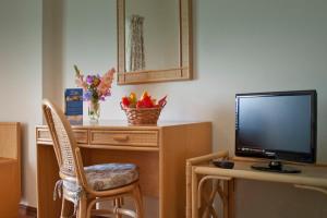 a living room with a tv and a desk with a chair at Alte Hotel in Alte