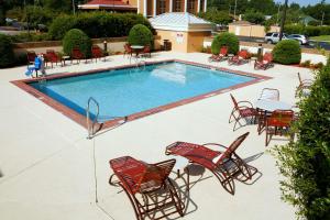 einen Pool mit roten Stühlen und Tischen sowie einem Tisch und Stühlen in der Unterkunft Best Western Plus Goldsboro in Goldsboro