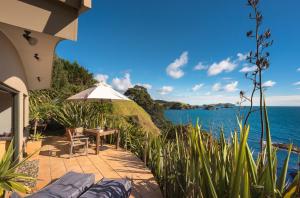 d'une terrasse avec une table, des chaises et l'eau. dans l'établissement Crab Cove, à Mahinepua