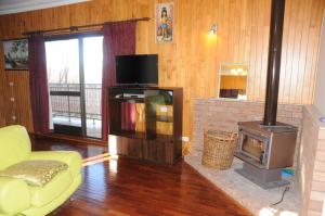 a living room with a fireplace and a television at Snowgate Motel + Apartments in Berridale