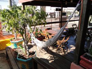 a hammock on a deck with a table and trees at Hostel Cuesta in Botucatu