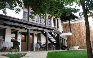a house with a deck and a table and chairs at Guest Rooms Bela Neda in Veliko Tŭrnovo