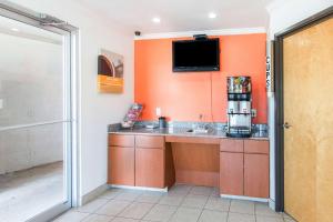 a kitchen with orange walls and a sink and a tv at Motel 6-Hutchins, TX in Hutchins