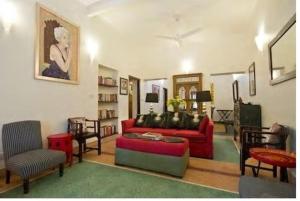 ein Wohnzimmer mit einem roten Sofa und Stühlen in der Unterkunft Zaza Stay in Neu-Delhi