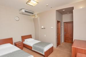 マグニトゴルスクにあるAvrora Hotelのベッドルーム1室(ベッド2台、壁掛け時計付)