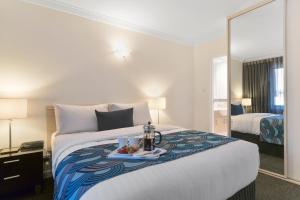 a hotel room with a bed and a dresser at The Peninsula Riverside Serviced Apartments in Perth