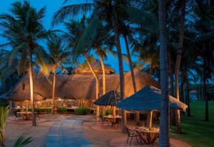 a resort with tables and palm trees at night at Radisson Blu Resort Temple Bay Mamallapuram in Mahabalipuram
