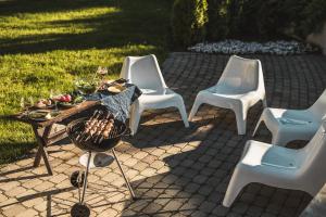 a group of white chairs and a table and a grill at Krauklis beach apartments in Saulkrasti