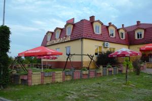 a building with red umbrellas in front of it at Hotel i Restauracja Jaskolka in Alojzów