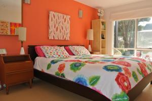 a bedroom with orange walls and a bed and a window at Clambake Beach House in Cape Woolamai