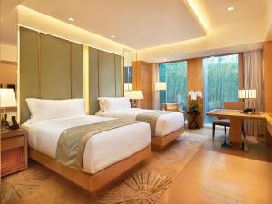 a hotel room with two beds and a desk and a desk at Pan Pacific Beijing in Beijing