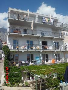 a large white building with people sitting on balconies at Apartments Viskovic in Makarska