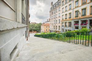 une rue de la ville avec des bâtiments et une clôture dans l'établissement Studio Jardin des Plantes Lyon1er, à Lyon