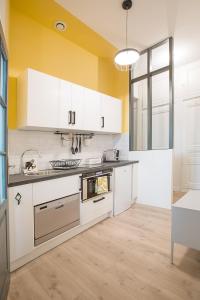 une cuisine avec des placards blancs et un mur jaune dans l'établissement Studio Jardin des Plantes Lyon1er, à Lyon
