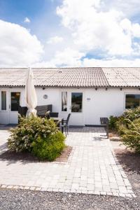 ein weißes Haus mit einer Terrasse und einem Sonnenschirm in der Unterkunft Kerteminde Byferie - Hyrdevej 83, 85B in Kerteminde