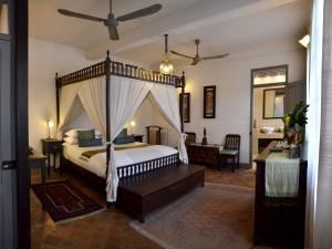 a bedroom with a canopy bed and a desk at Satri House Hotel in Luang Prabang