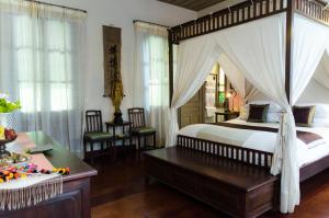 a bedroom with a canopy bed and a desk at Satri House Hotel in Luang Prabang