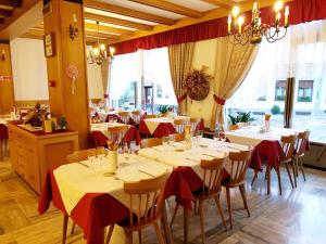 a dining room with tables and chairs with red tablecloths at Albergo Posta in Colle Santa Lucia