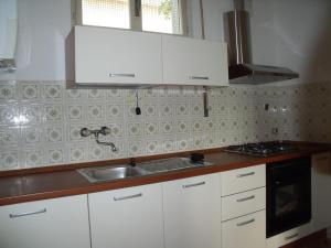 a kitchen with white cabinets and a sink at Casa Irene in Perledo