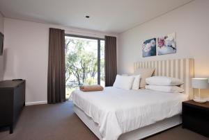 
a bedroom with a large bed and a large window at Aqua Resort Busselton in Busselton
