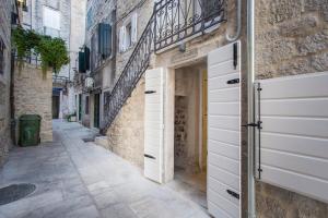 Une allée dans une vieille ville avec des portes blanches dans l'établissement Mijama suites, à Split