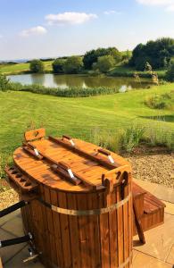 a wooden tub sitting on a patio next to a lake at Fair Farm Hideaway in Waltham on the Wolds