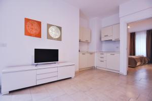 a kitchen with white cabinets and a flat screen tv at BB Hotels Aparthotel Visconti in Milan