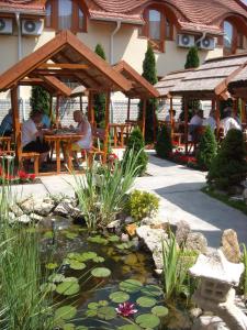 a pond in a garden with people sitting at a table at Fodor Hotel in Gyula