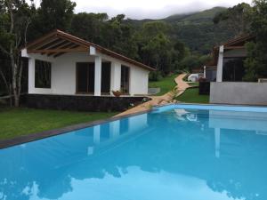 a villa with a swimming pool in front of a house at Villas Casteletes in Urzelina