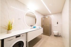 a white bathroom with a washer and dryer in it at Benetis apartments in Klaipėda