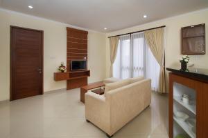 a living room with a chair and a television at Pondok Massas Ubud in Ubud