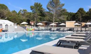 une grande piscine avec chaises longues et parasols dans l'établissement VVF Montagnac Hérault, à Montagnac