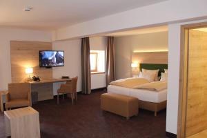 a hotel room with a bed and a desk and a television at SPIEGLHOF apart in Kumhausen