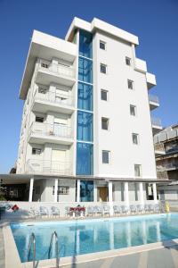 a large white building with a swimming pool in front of it at Hotel Al Ragno in Cesenatico