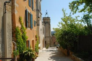 an alley in a town with buildings and trees at Au Bon Penequet in Pujaut